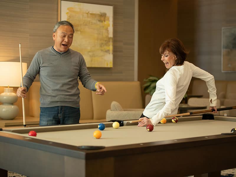 Couple playing billiards.